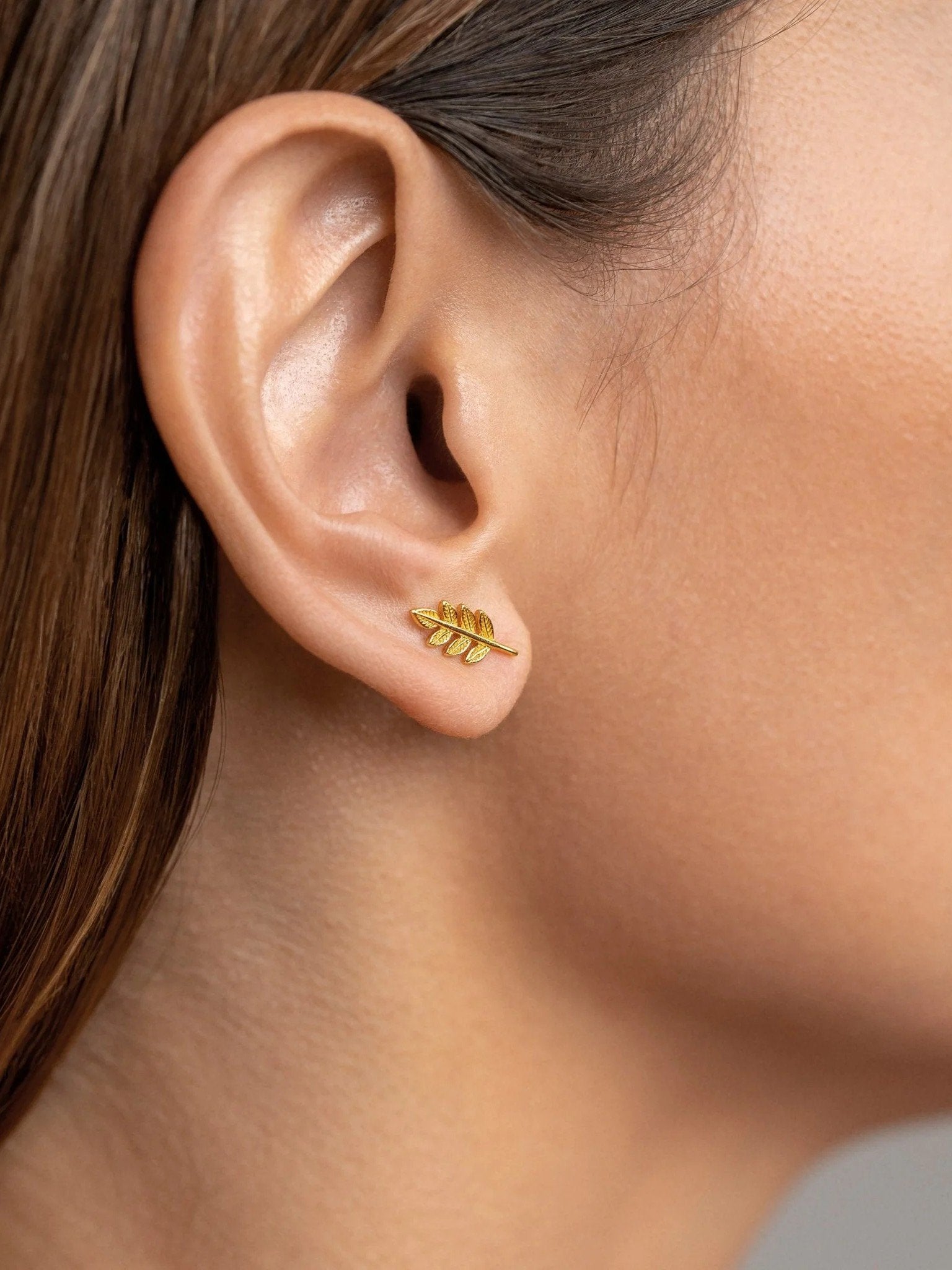Gudrun gold leaf stud earrings worn — elegant botanical shape on ear.