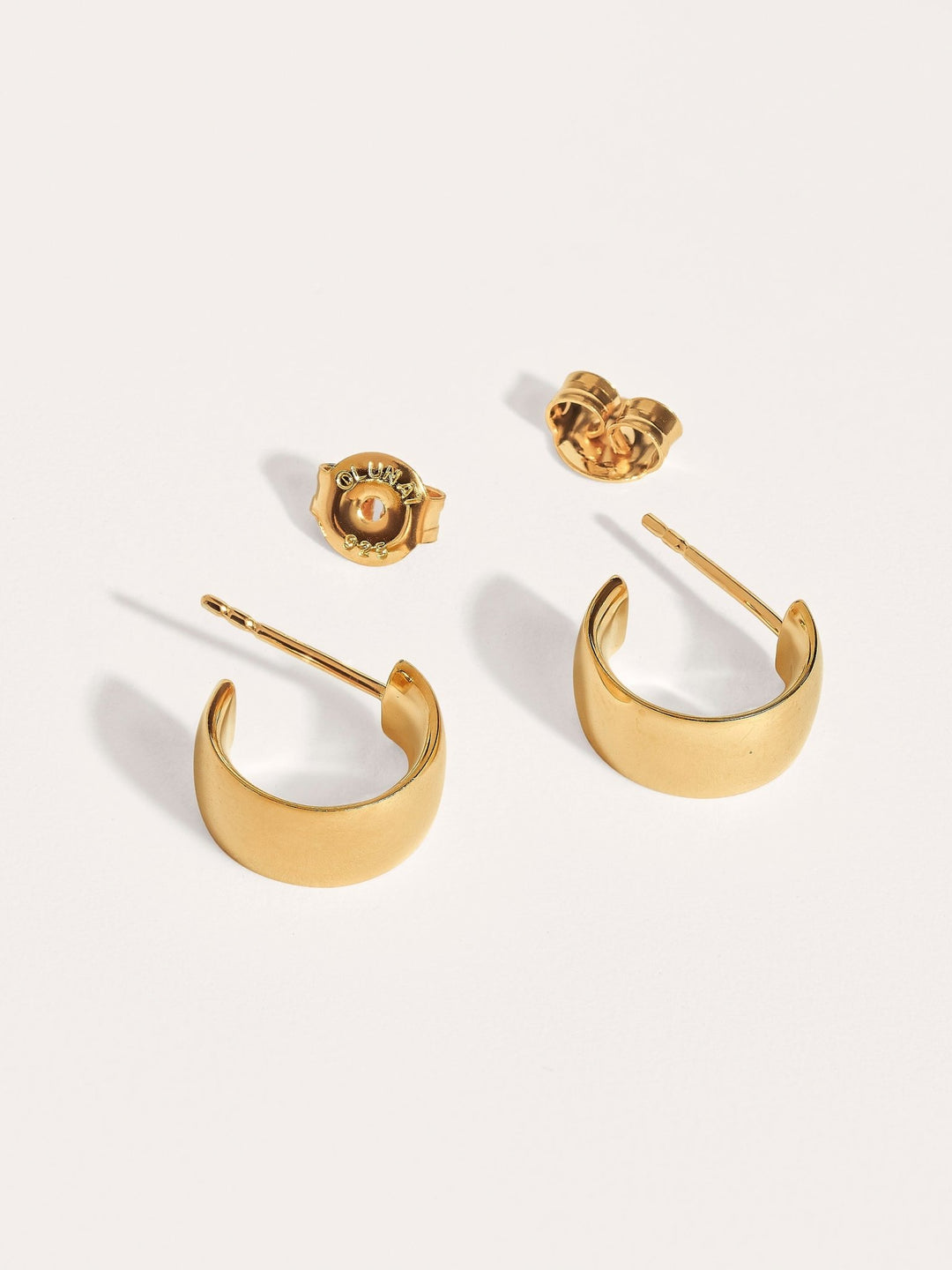 Pair of bold gold hoop earrings with screw backs on white background.