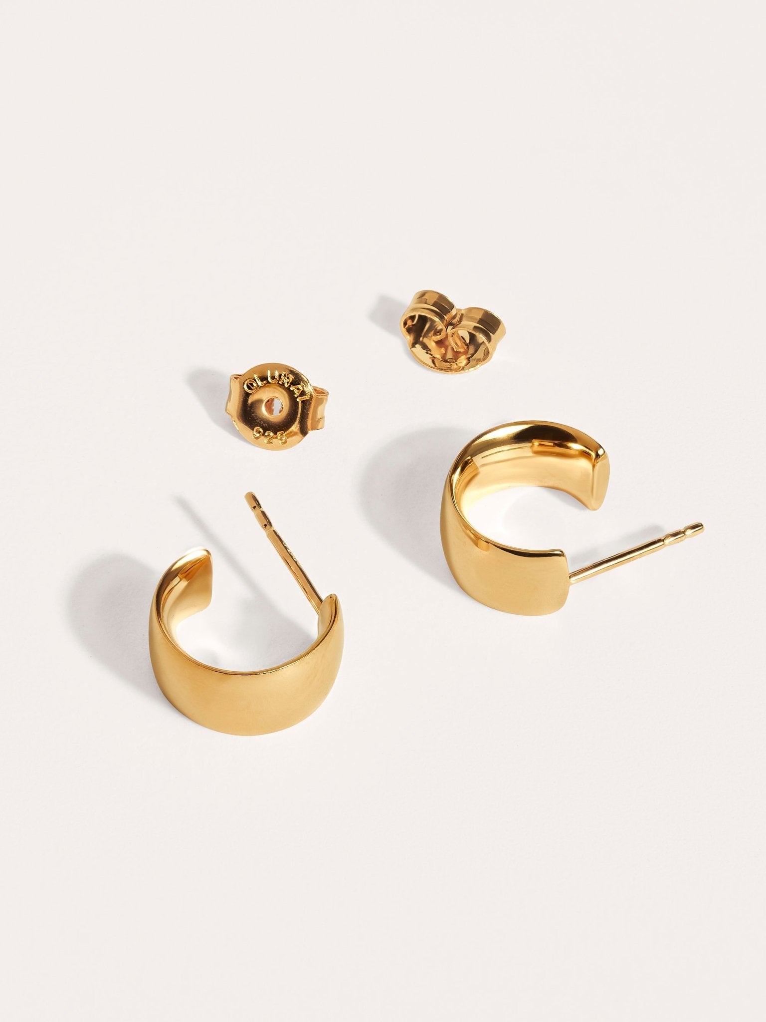 Chunky gold hoop earrings with butterfly backs, minimalist flat-lay.