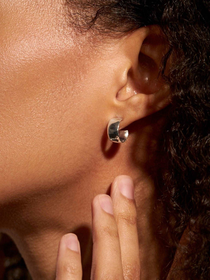 Woman wearing chunky sterling silver 925 hoop earring, close-up side view.