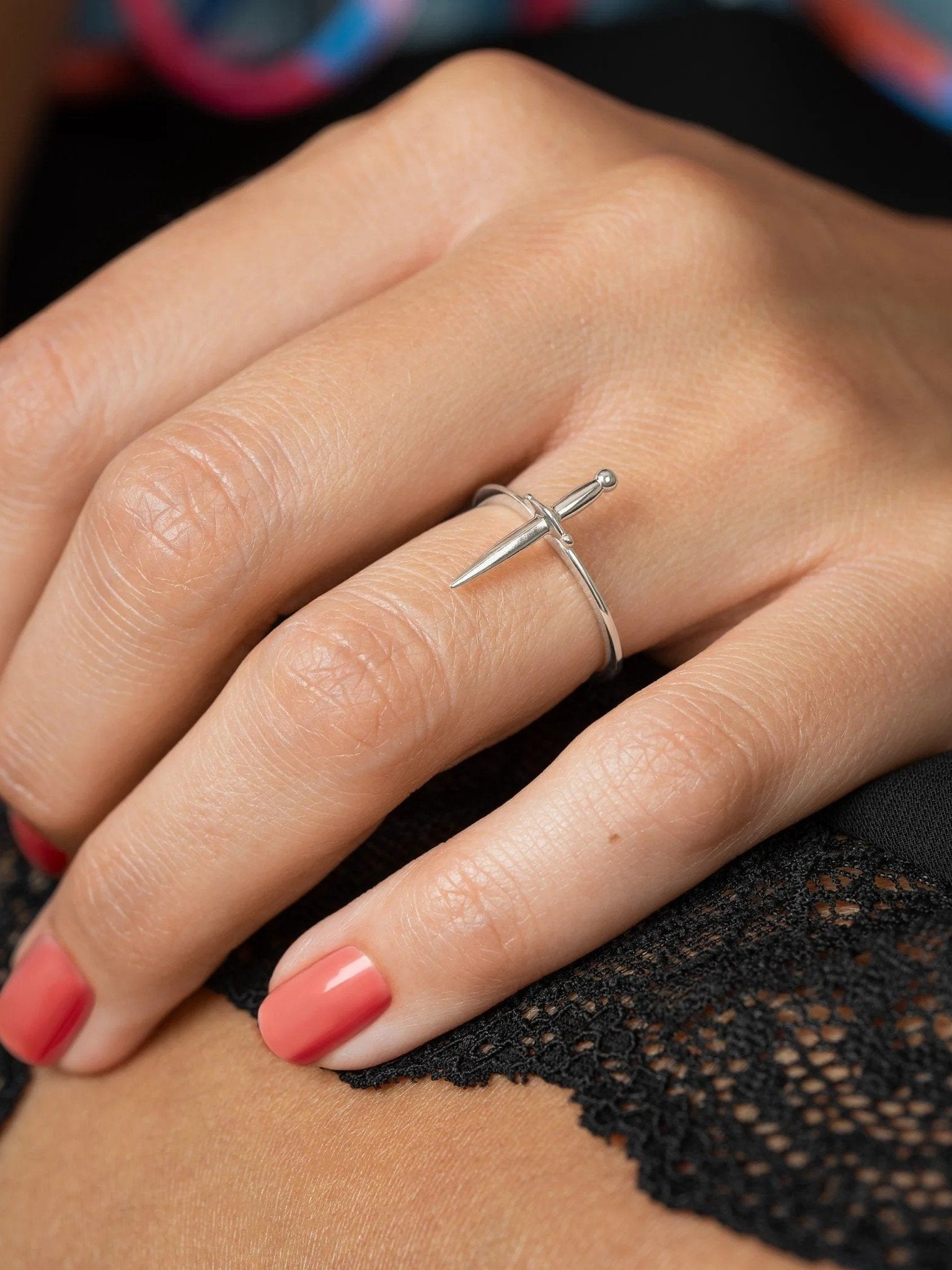 Silver dagger ring styled on hand with red nails, evoking a modern renaissance vibe.