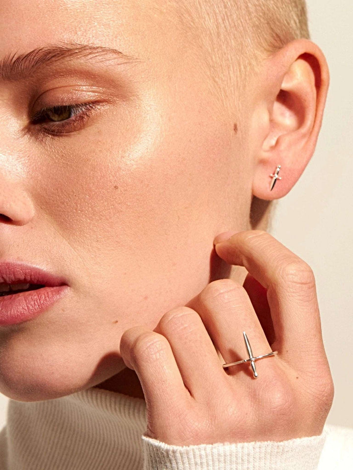 Close-up portrait of woman wearing the dagger ring in silver, resting hand on face.