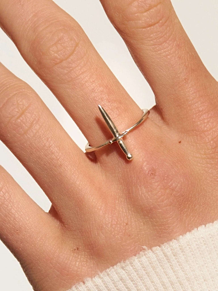 Sterling silver dagger ring worn on index finger, styled with a soft knit top.