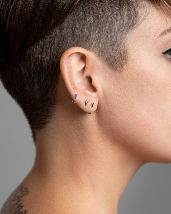 Luppa hug hoop earrings worn in sterling silver, rose gold plated, and oxidized silver — layered minimalist look with sculptural contrast.