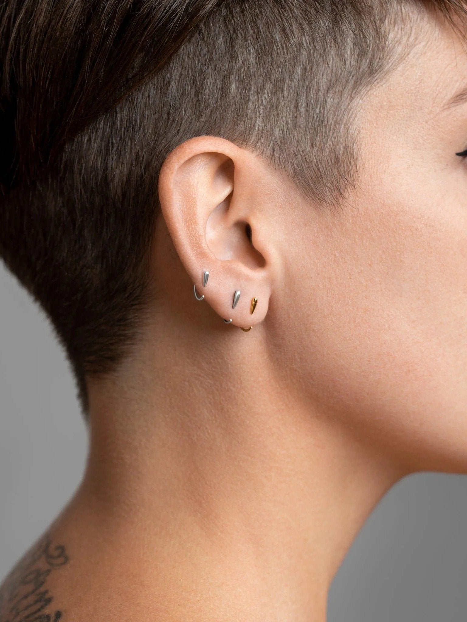 Luppa hug hoop earrings worn in sterling silver, rose gold plated, and oxidized silver — layered minimalist look with sculptural contrast.