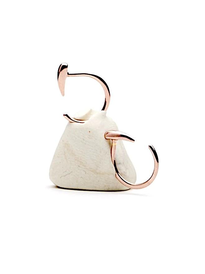 Luppa hug hoop earrings in rose gold plated finish — sculptural and delicate design displayed on a neutral stone.