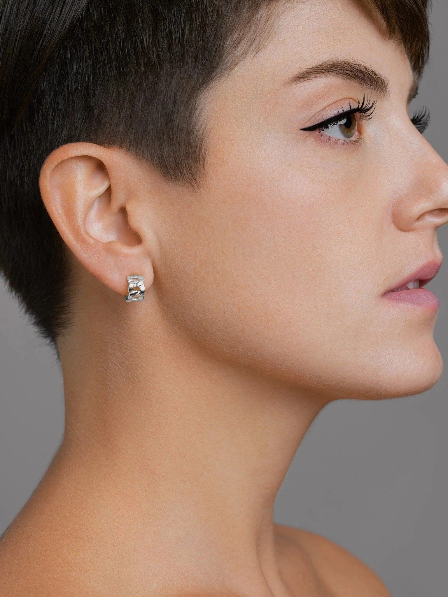 Right-side view of the Meel Gold Hoop Earrings styled on a model with pixie cut, showcasing their sculptural chain-inspired form.