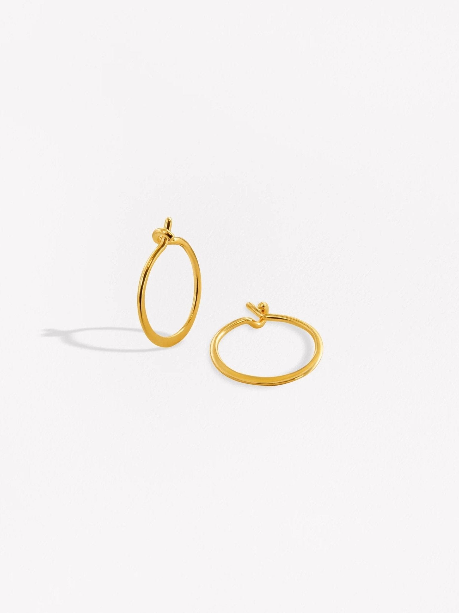 Gold hoop earrings with a unique open design on a white background.