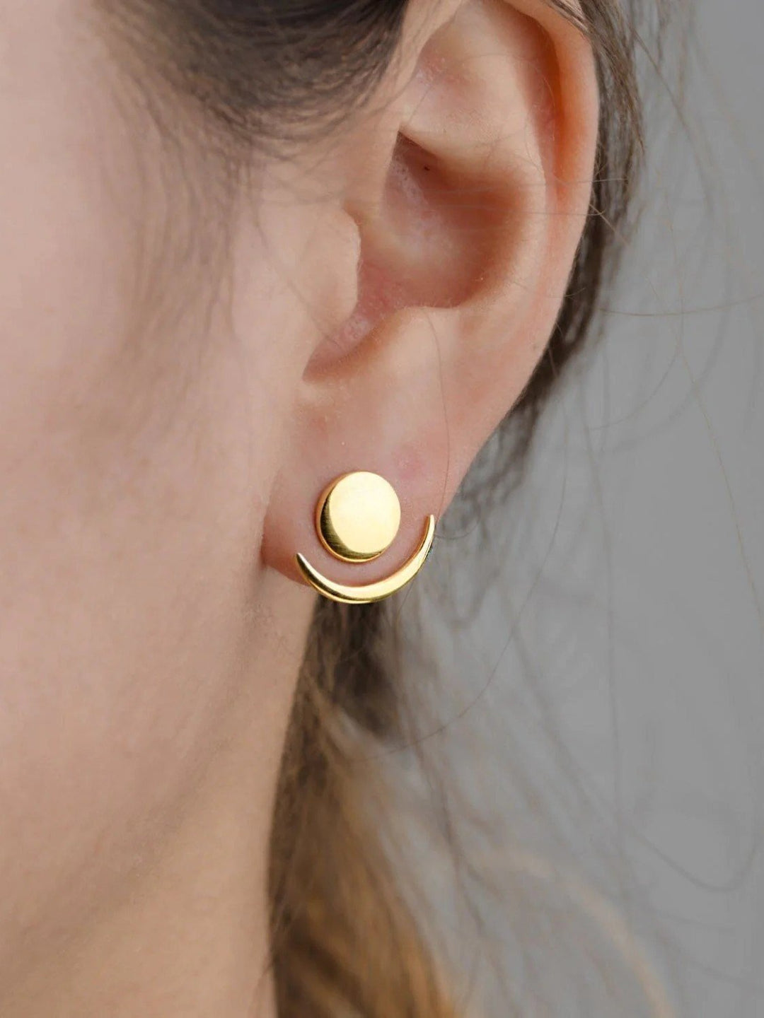 Gold shiny ear jackets with a versatile design, close-up on a model with tied-back hair.