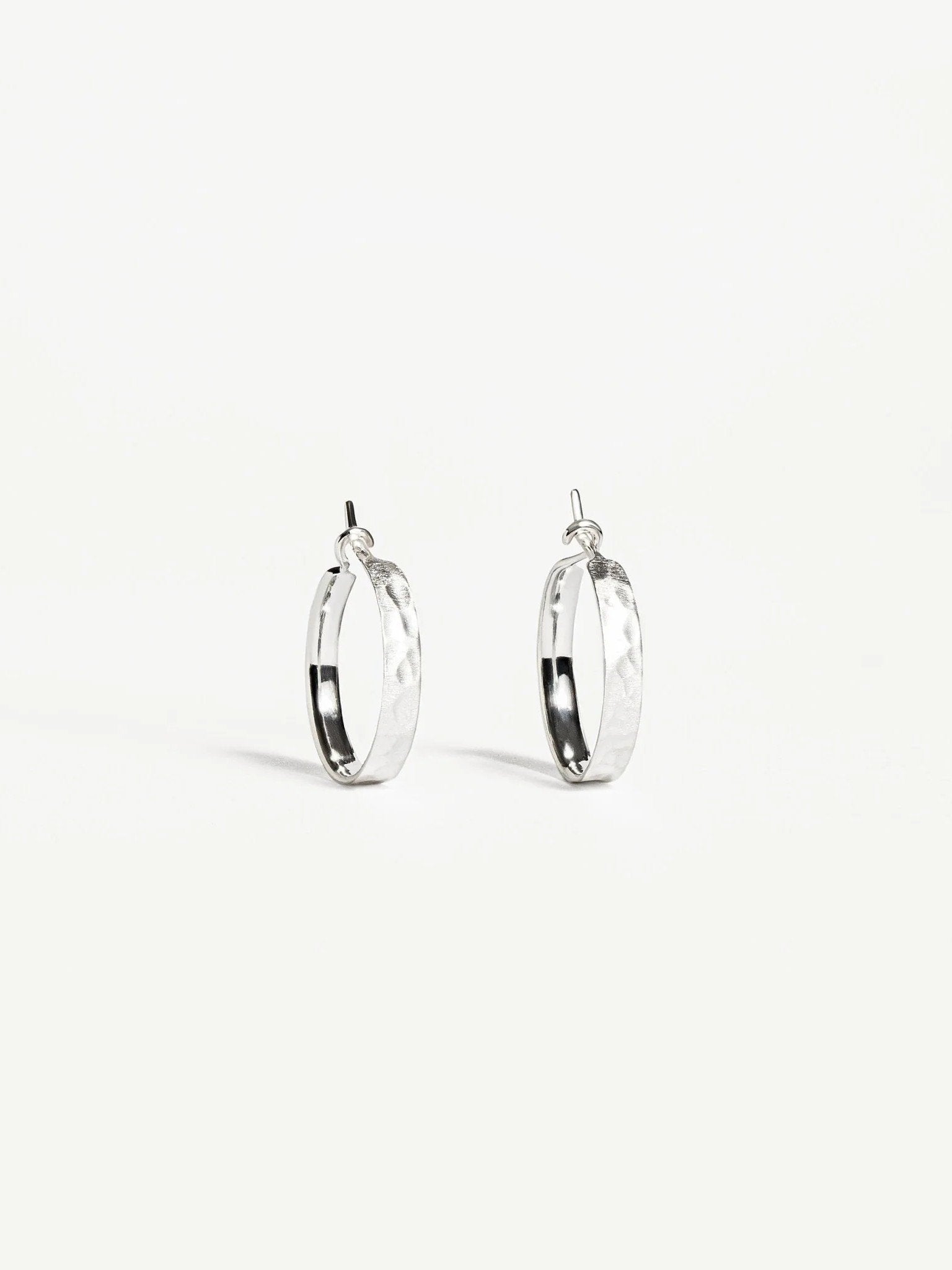 Nanna huggie hoops in matte sterling silver — hammered surface with minimalist style.