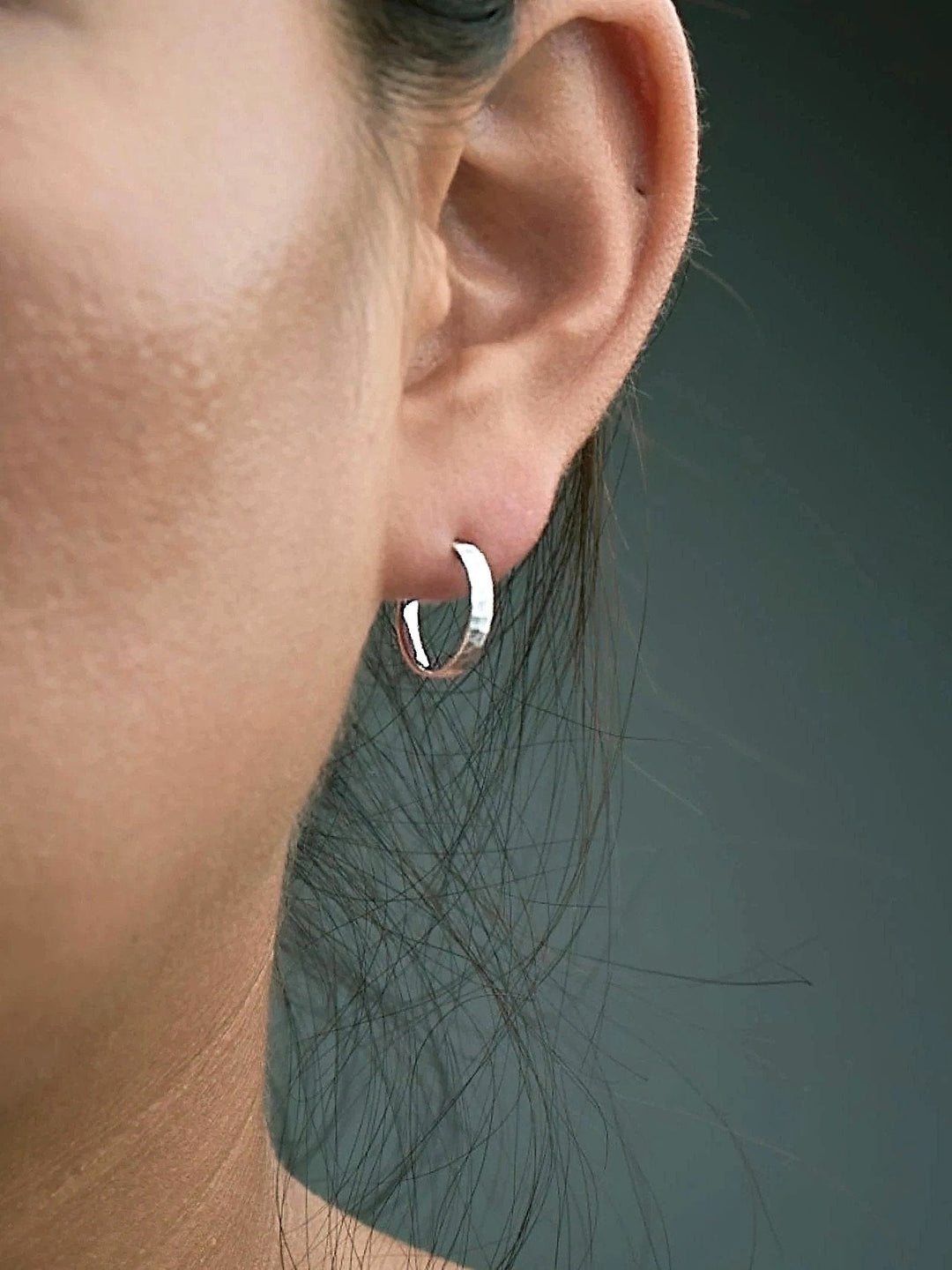 Nanna matte sterling silver huggie hoop worn on tragus — subtle texture and understated shine.