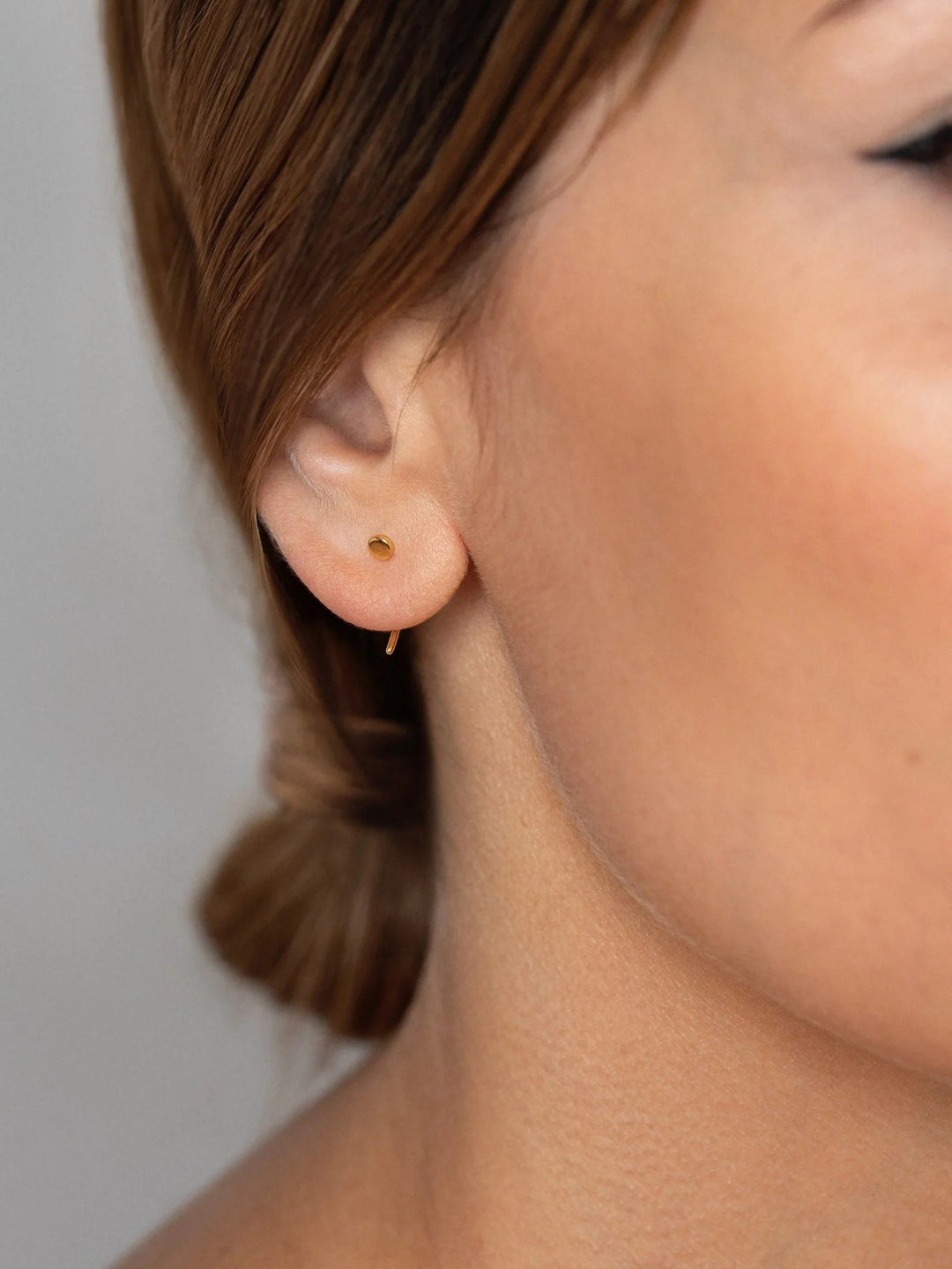 Side view of a model wearing gold open hoop earrings, elegant and dainty.