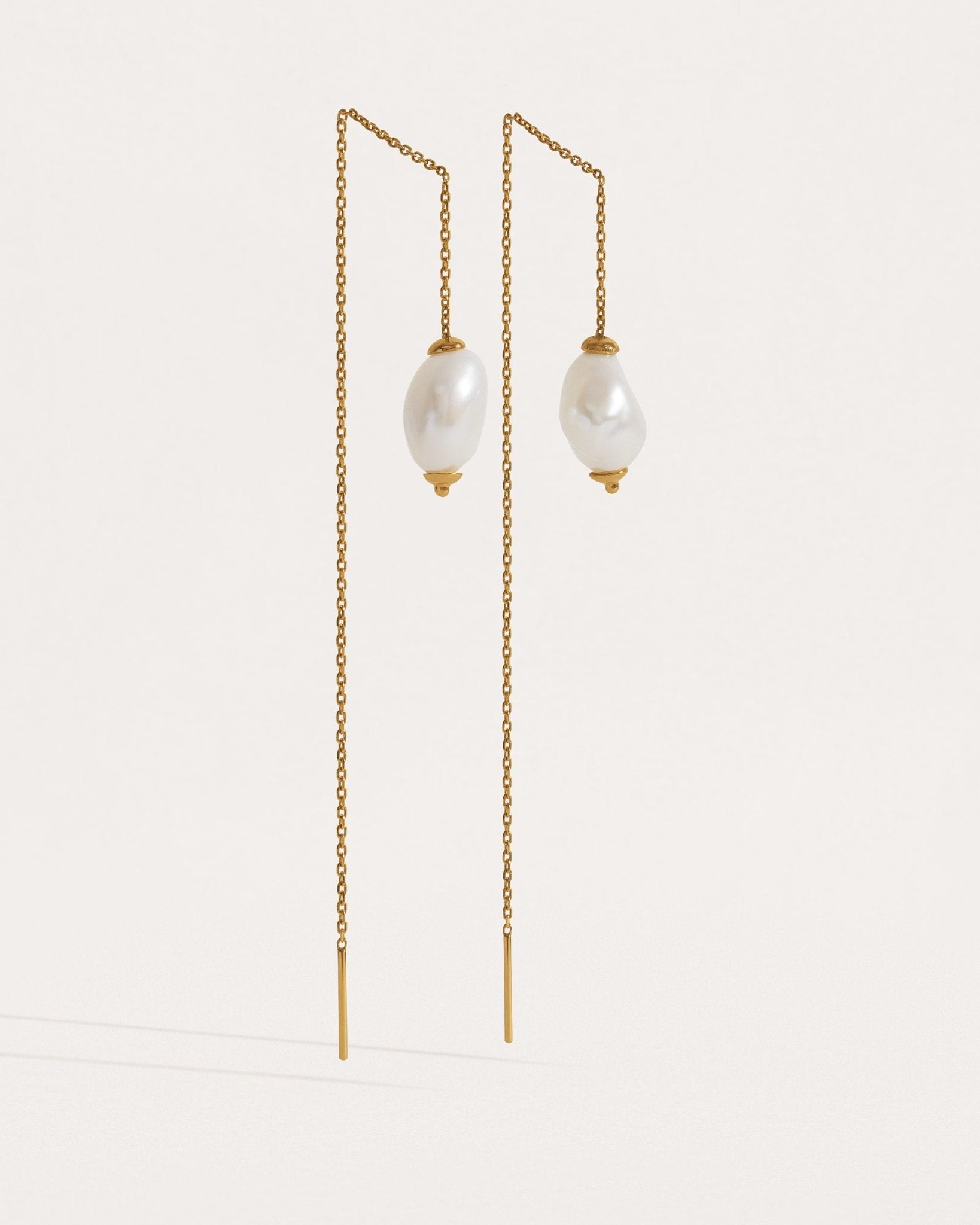 Two pairs of threader earrings in silver and gold finishes — freshwater pearl drops on fine chain.