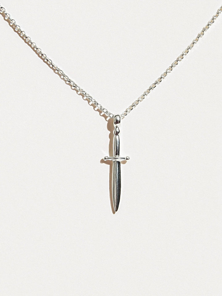 Sterling silver dagger necklace hanging on white background, clean full view.