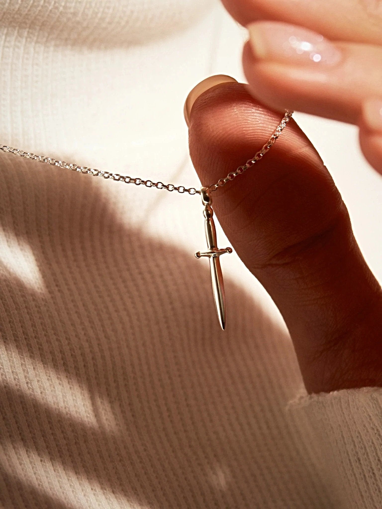 Sterling silver dagger necklace worn with soft knit top, clean and refined look.