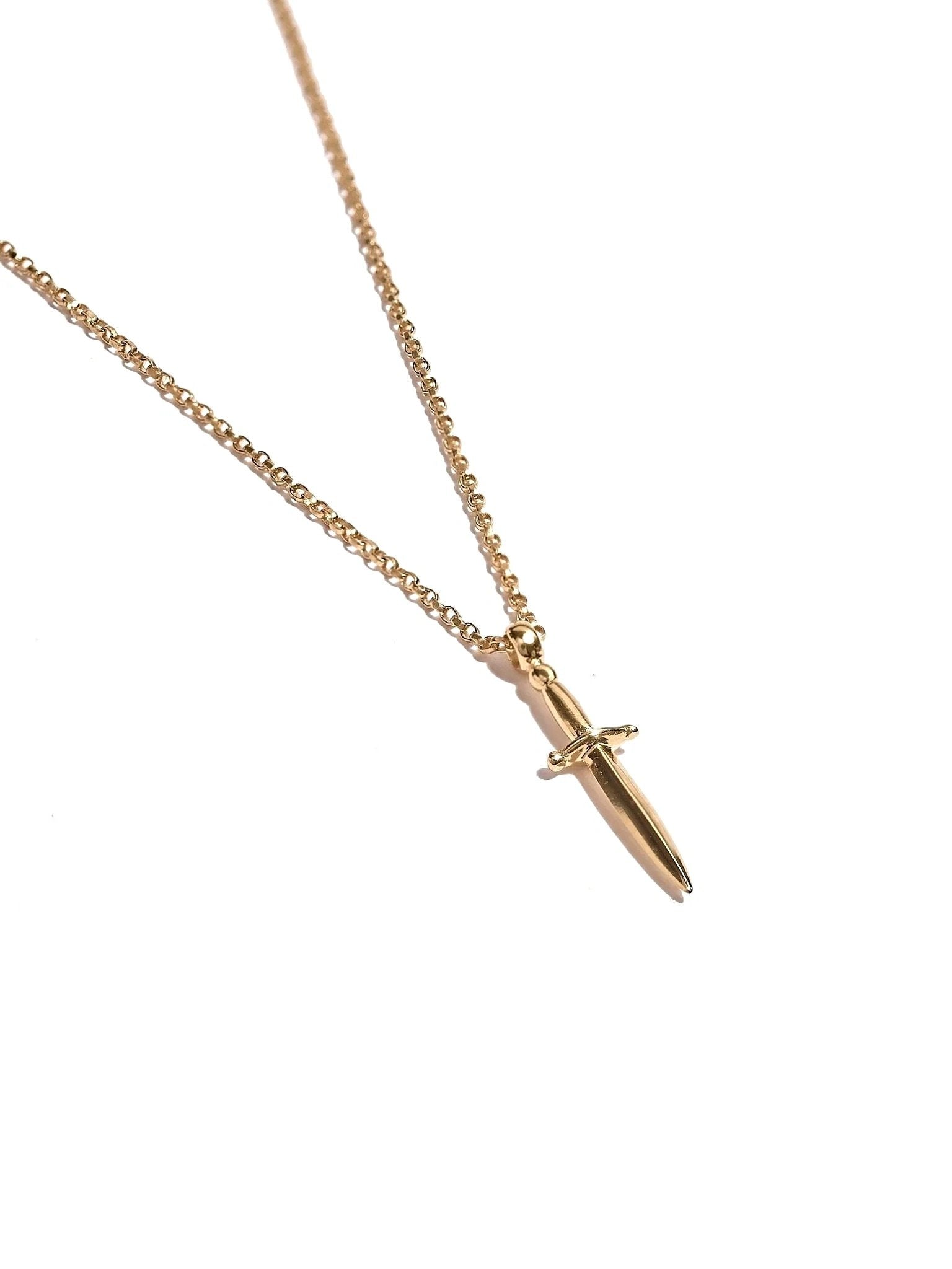 Gold vermeil dagger necklace laid flat in soft diagonal composition, minimalist and elegant.