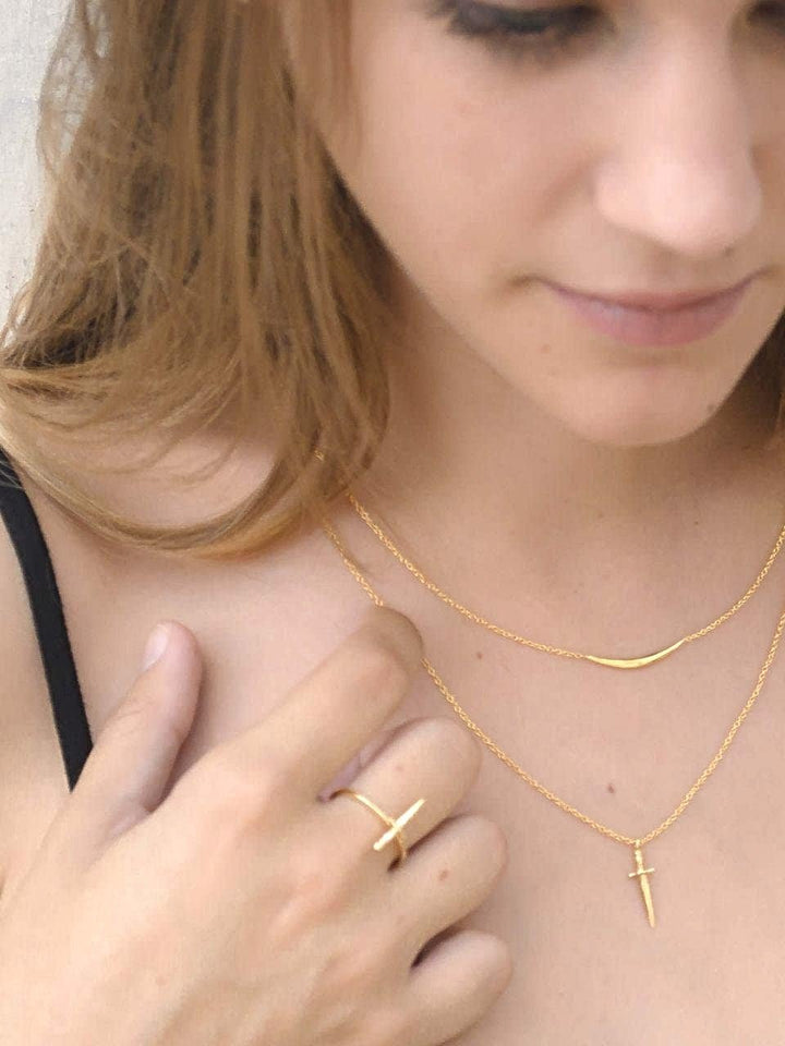 Model wearing layered gold necklaces, smiling softly, casual and natural.