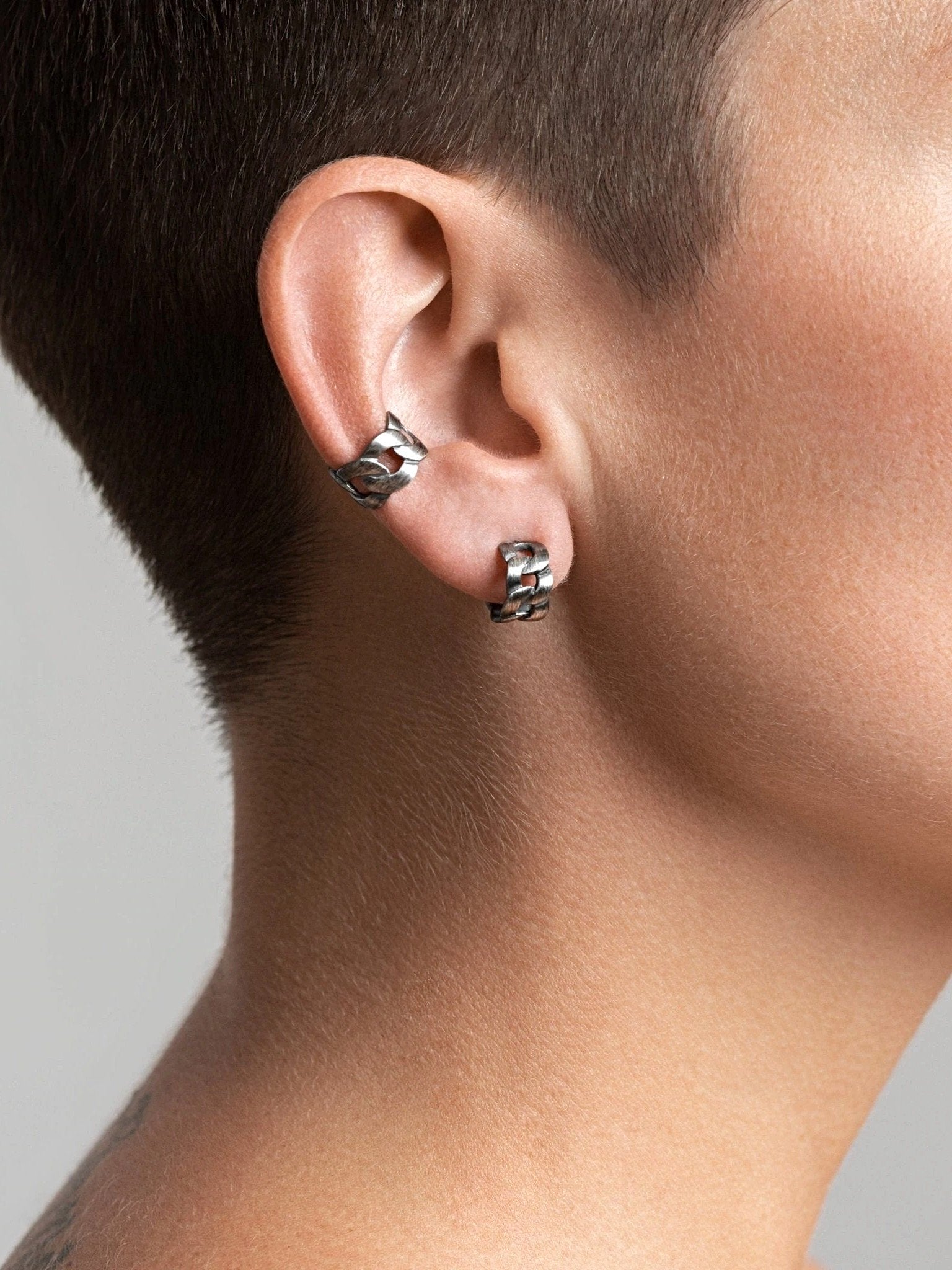 Side view of Renatte silver oxide ear cuff — sculptural chain design worn alone.