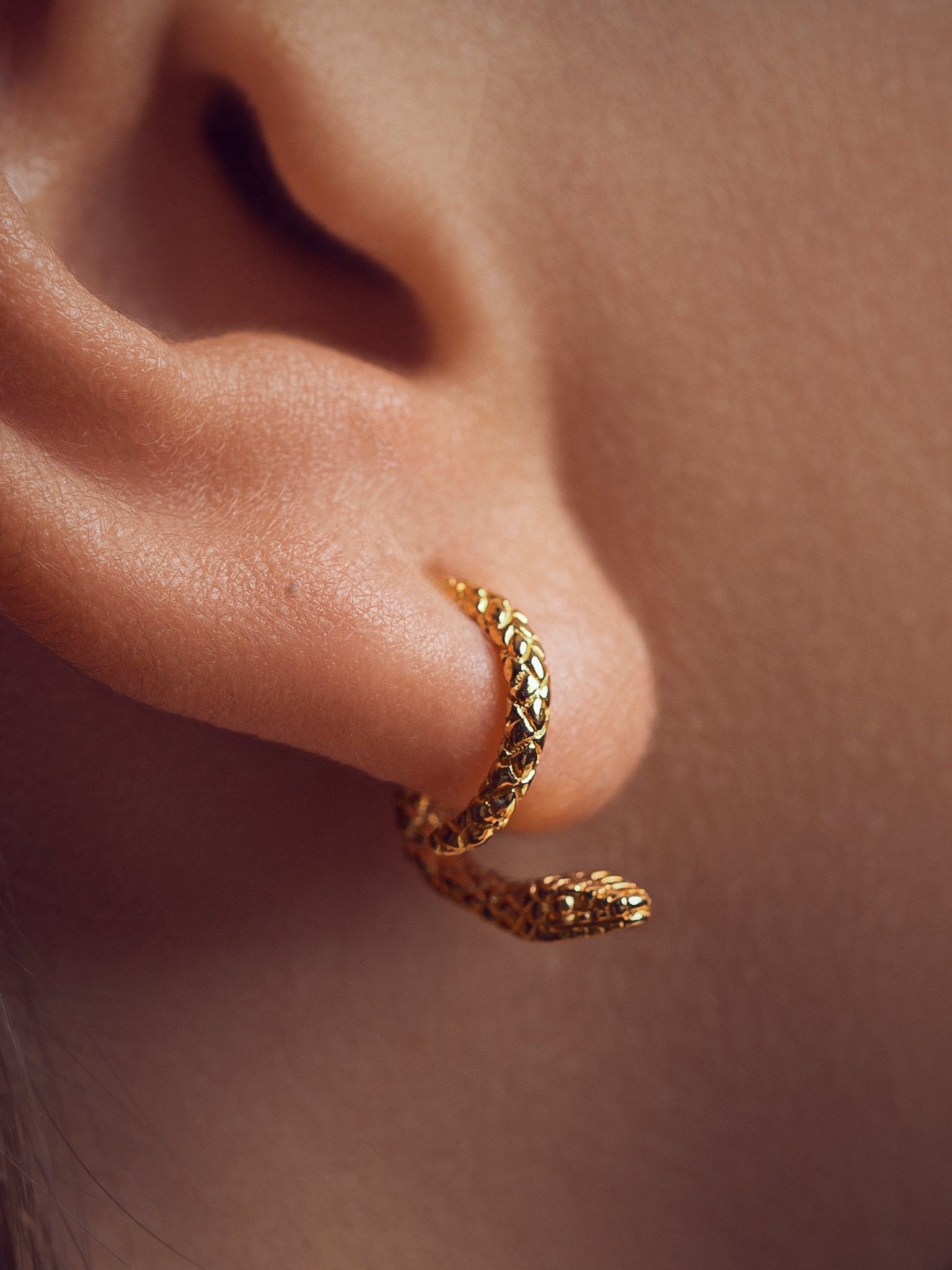 Close-up of the 24K gold plated snake ear jacket, highlighting its sleek curves and refined texture.