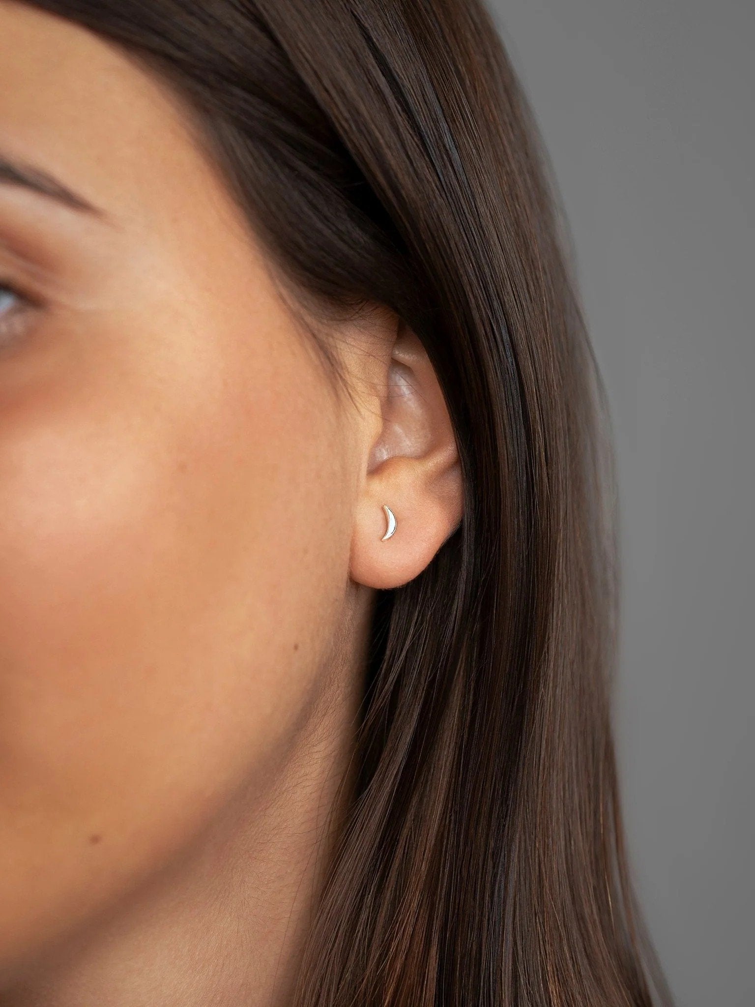 Model wearing one 925 sterling silver crescent stud earring from three-piece set