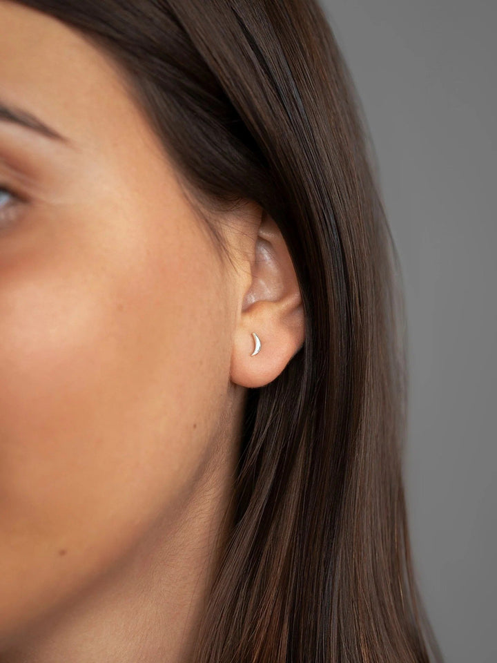 Model wearing one 925 sterling silver crescent stud earring from three-piece set
