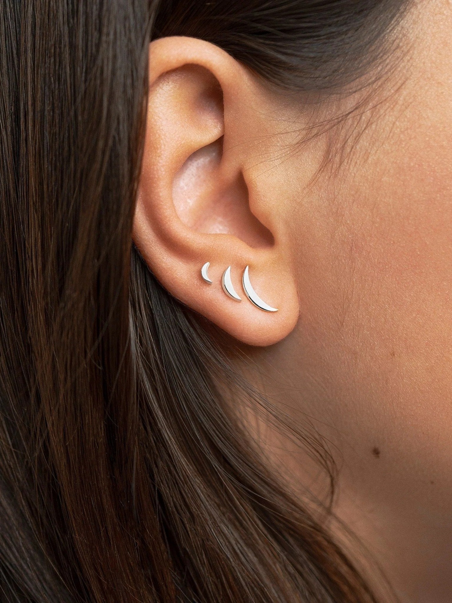 Model wearing silver three-piece crescent earring set close-up