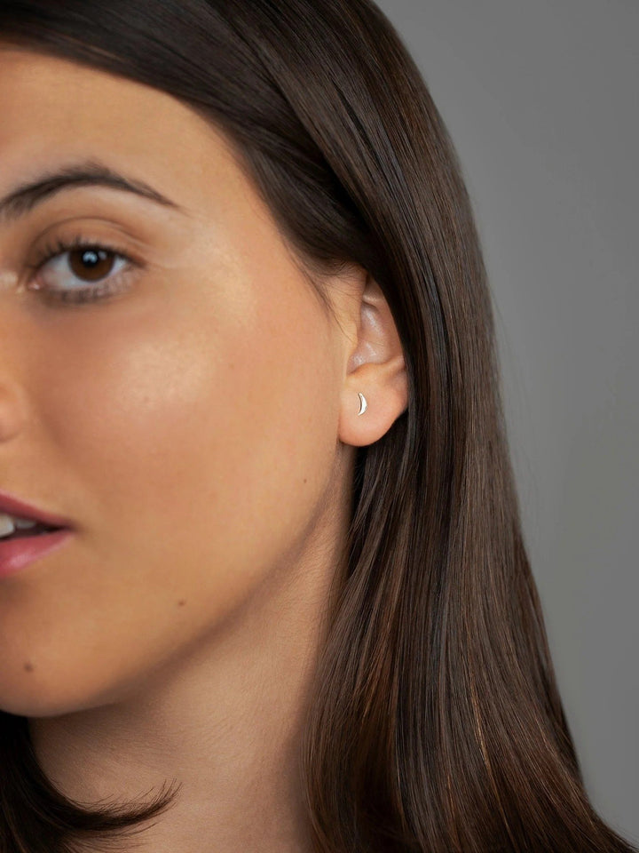 Side profile of model wearing silver three-piece crescent studs