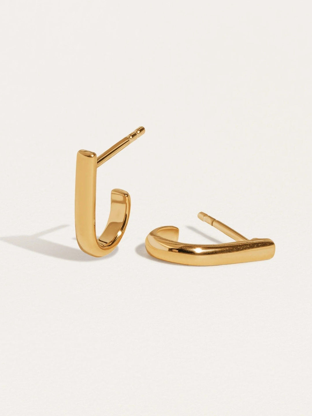 Pair of Sita bar earrings in 24K gold plated finish — minimalist sculptural shape on white background.