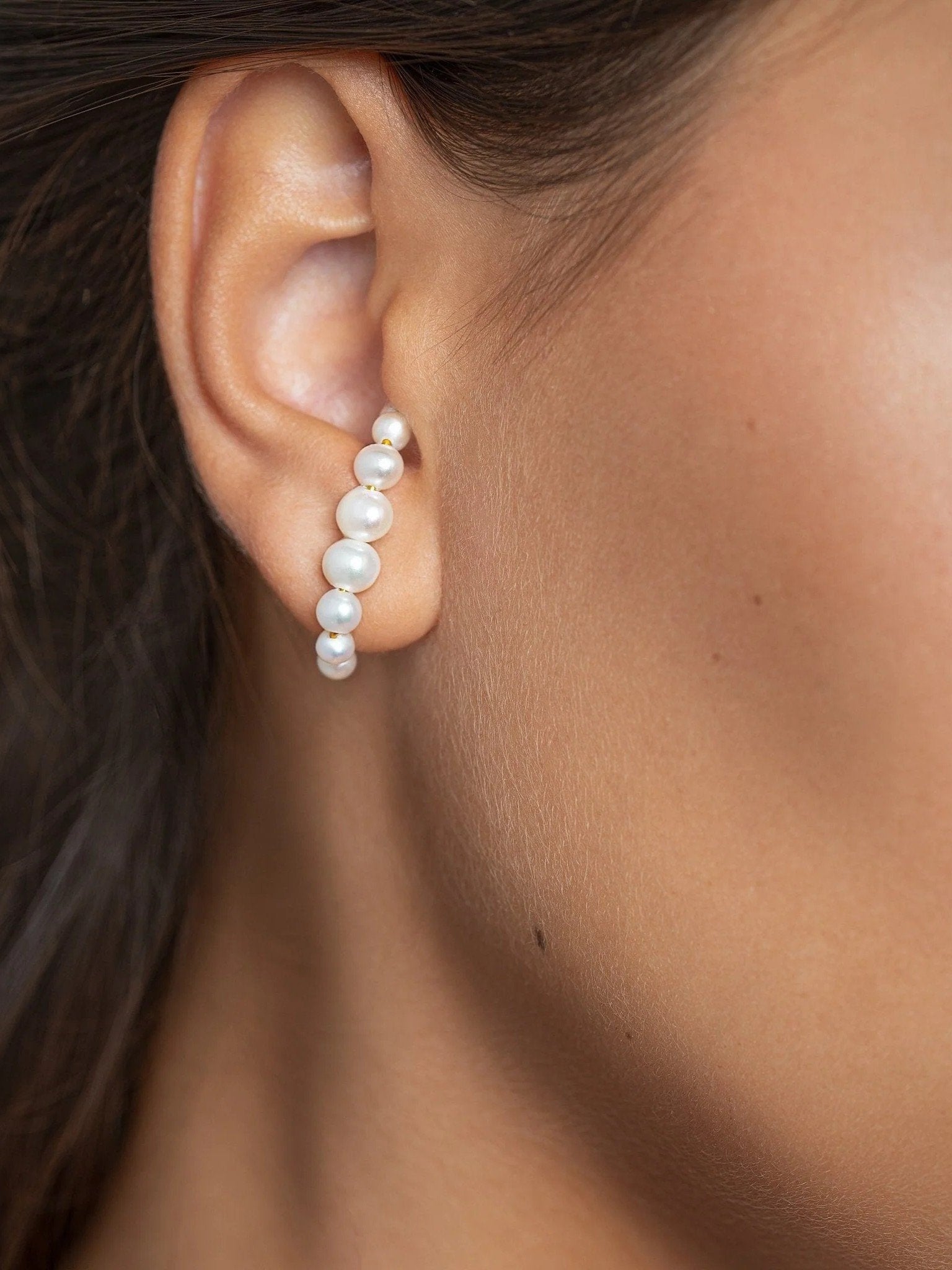 Woman wearing the Solene handmade pearl ear cuff, showing how it gently hugs the ear without piercing.