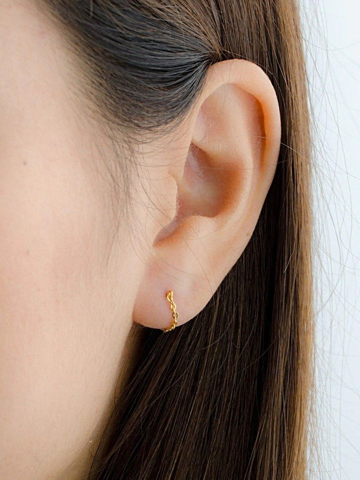 Woman wearing gold chain stud earring, close-up