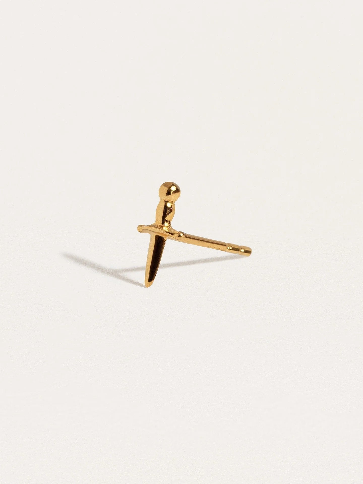 Gold-plated Tessa Sword Stud Earrings held in hand for size reference"
