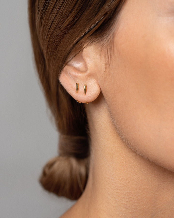 Luppa gold earring worn — polished finish and hugging shape styled close to ear.