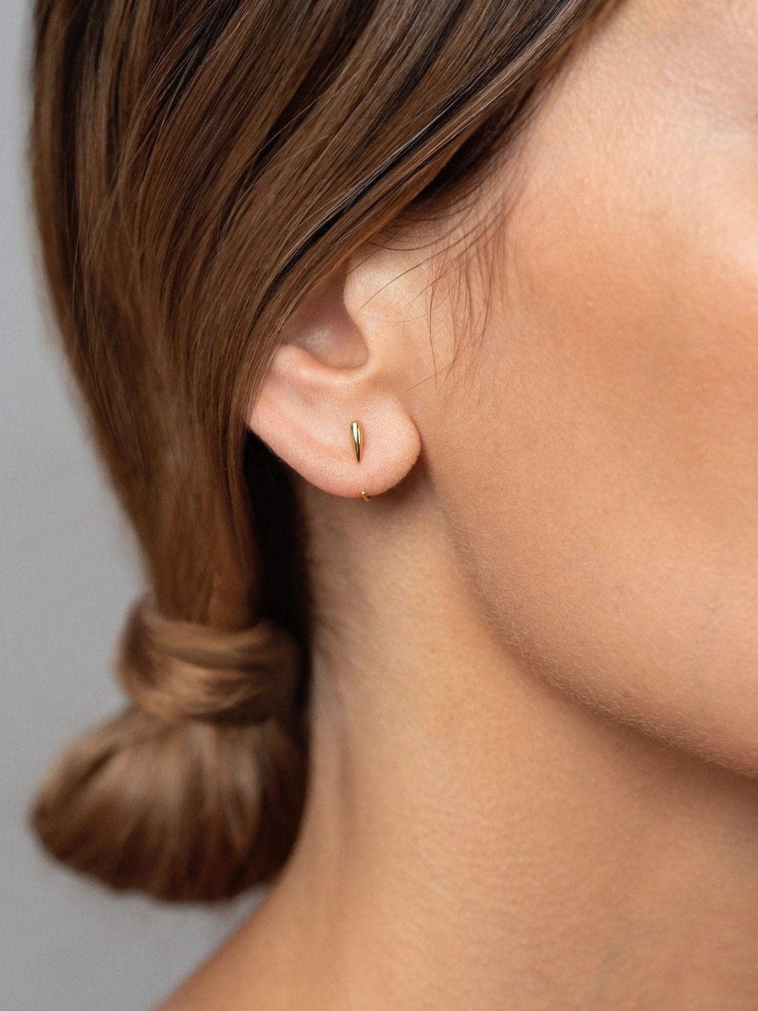 Luppa gold hug hoop earring worn — modern, minimal styling with soft glow.