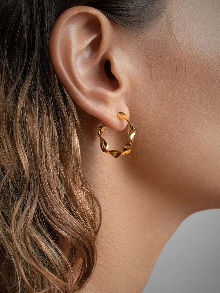 "Model wearing Gene Twisted Hoop Earrings in gold, front view with soft lighting"