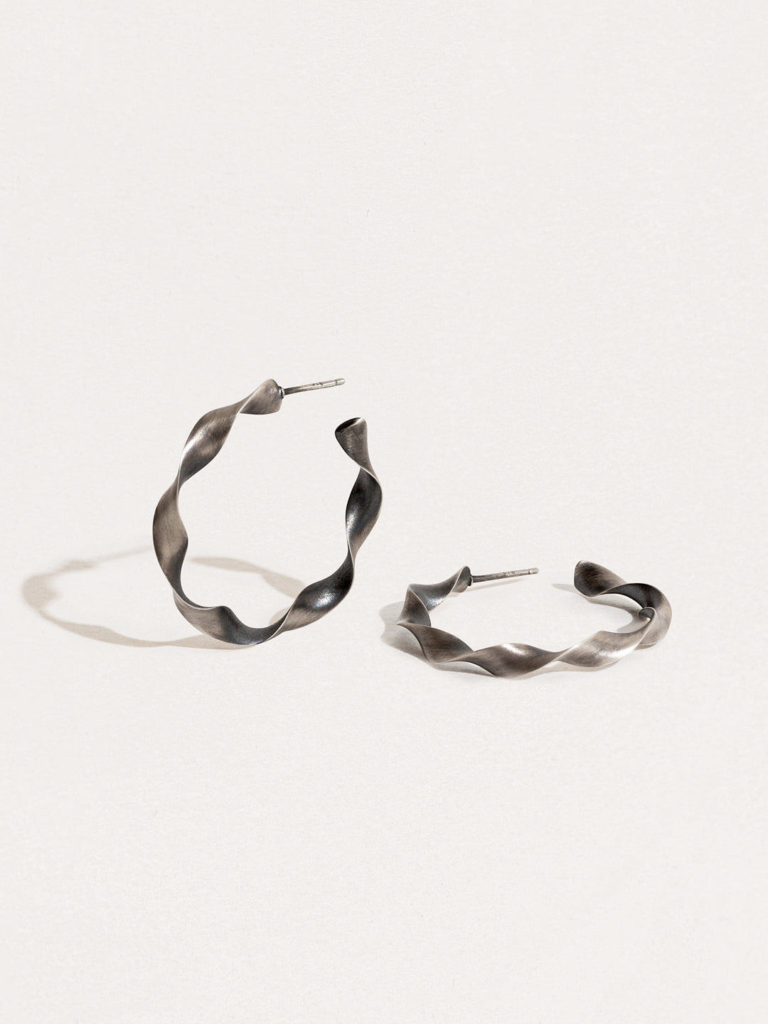 "Close-up of Gene Twisted Hoop Earrings in silver oxide showing texture and design details"