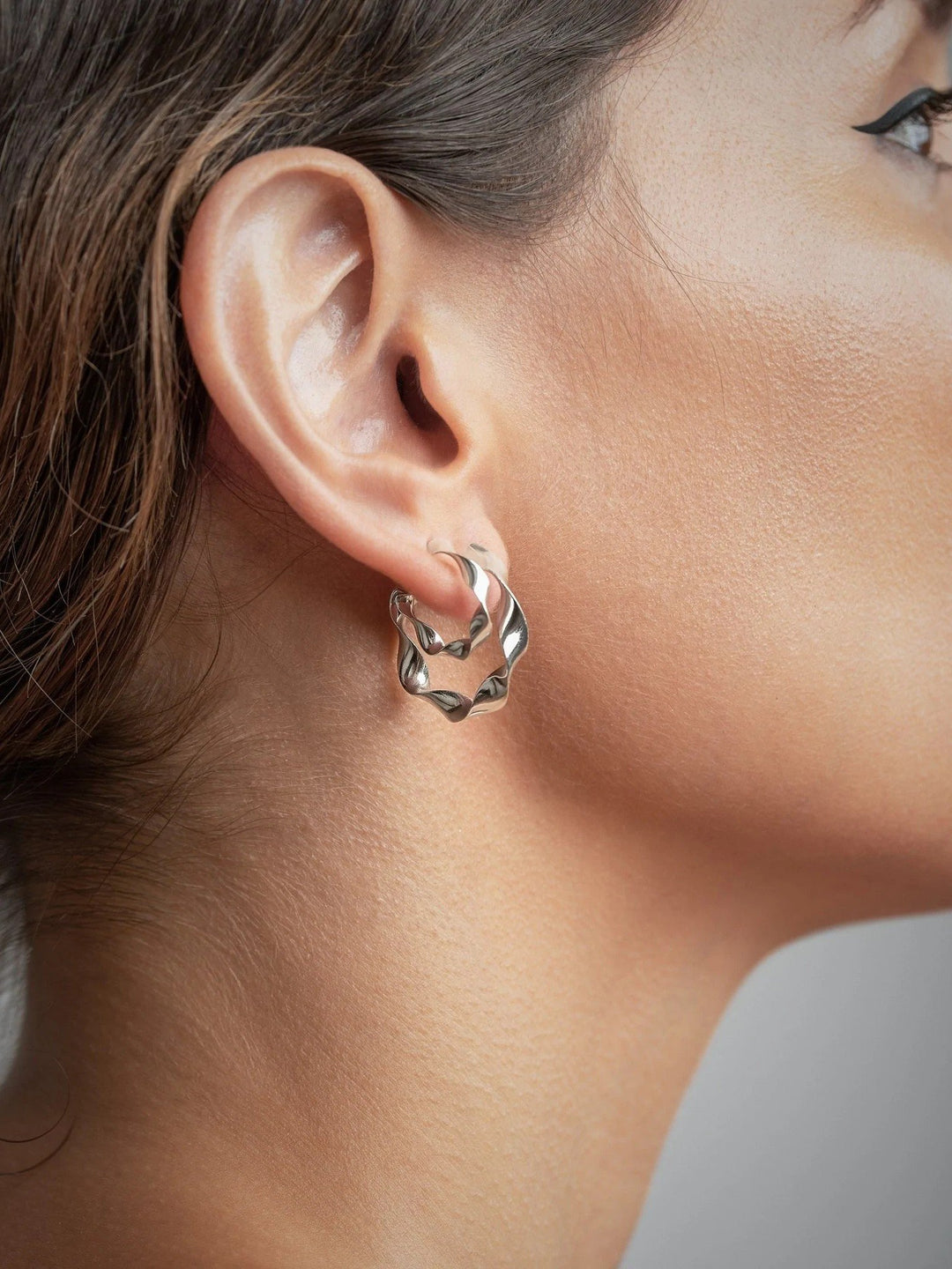 "Model wearing Gene Twisted Hoop Earrings, close-up showing details of the earrings"