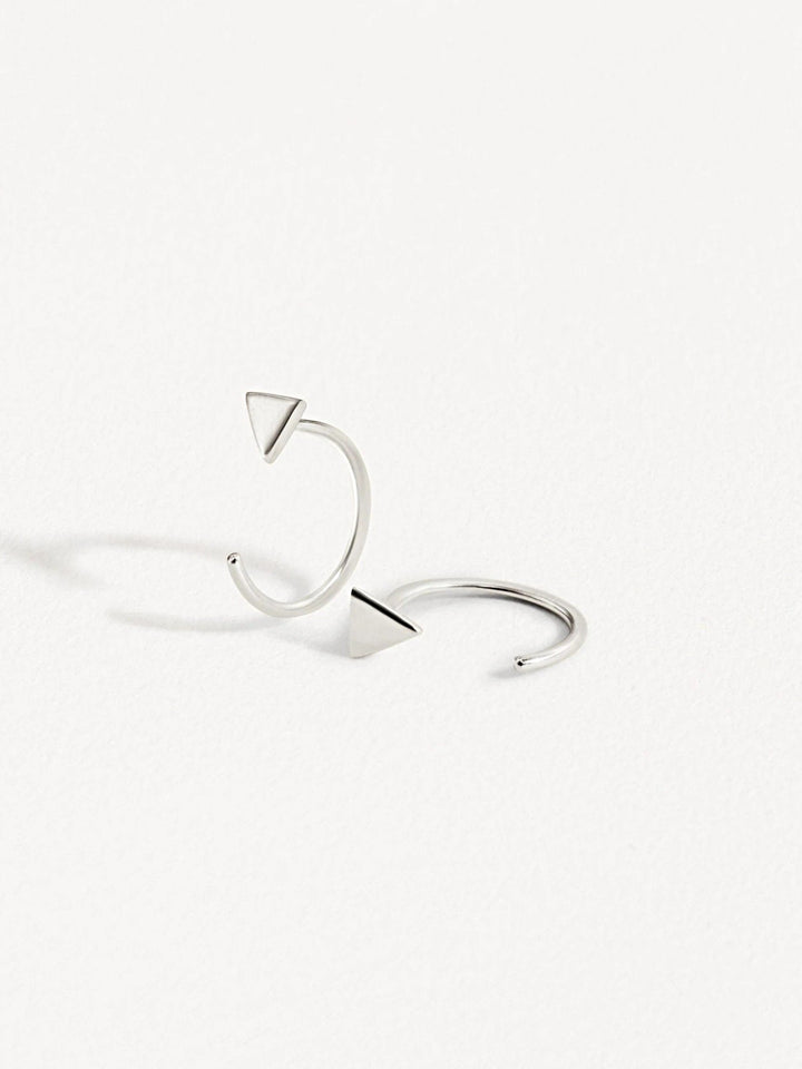 Pair of silver geometric triangle huggie earrings on white background