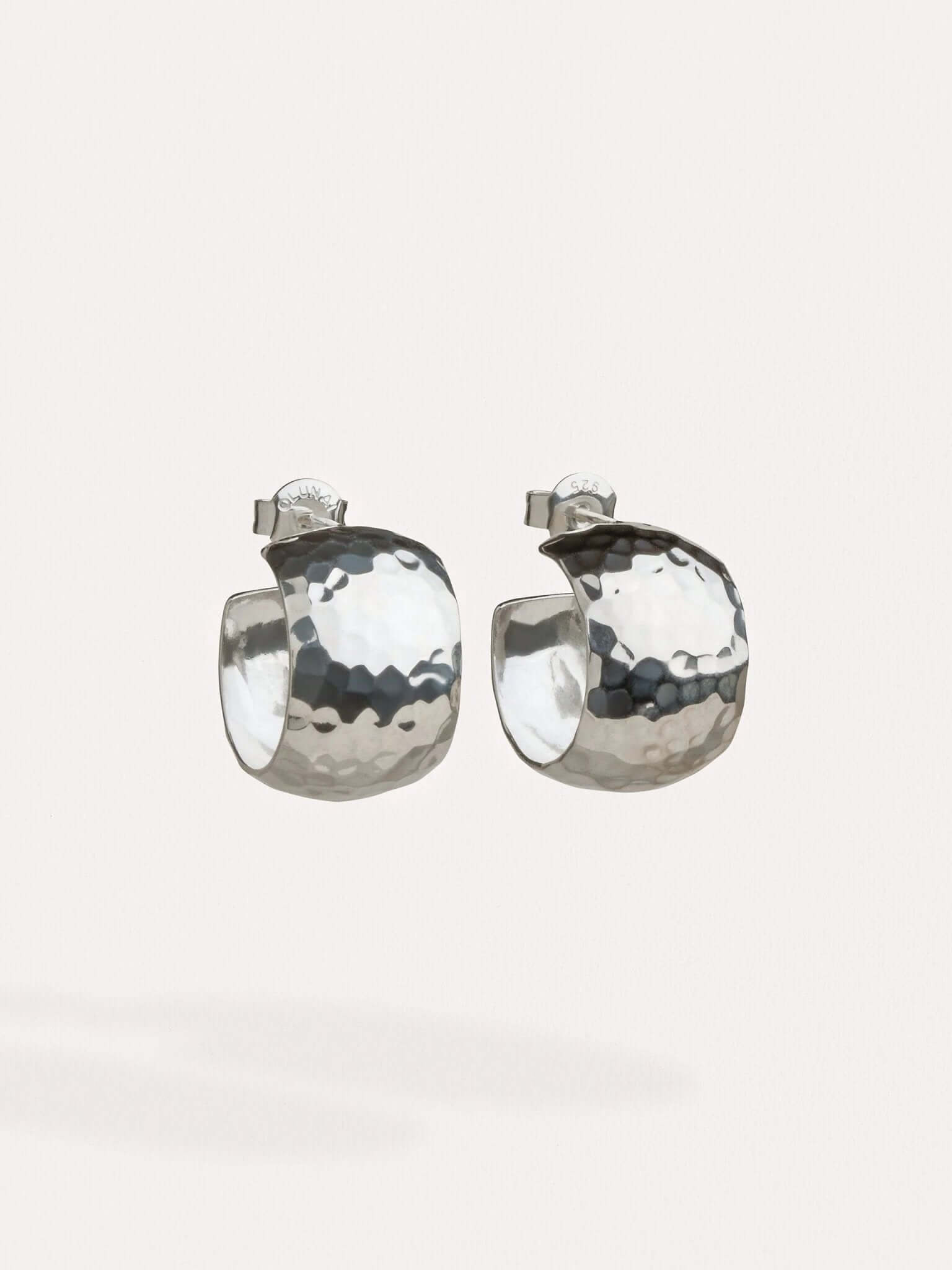 Model wearing sterling silver wide hoop earrings, bold yet elegant design.