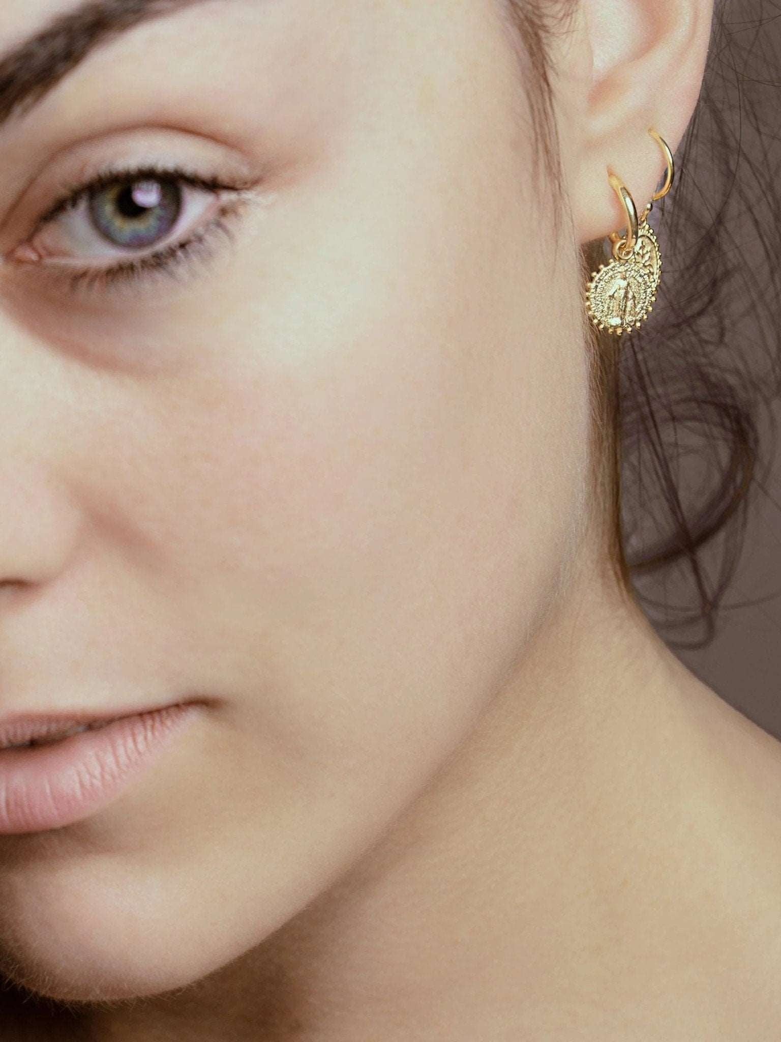 Model wearing gold plated Codi Mini Hoops – elegant and meaningful jewelry with Virgin Mary charm.