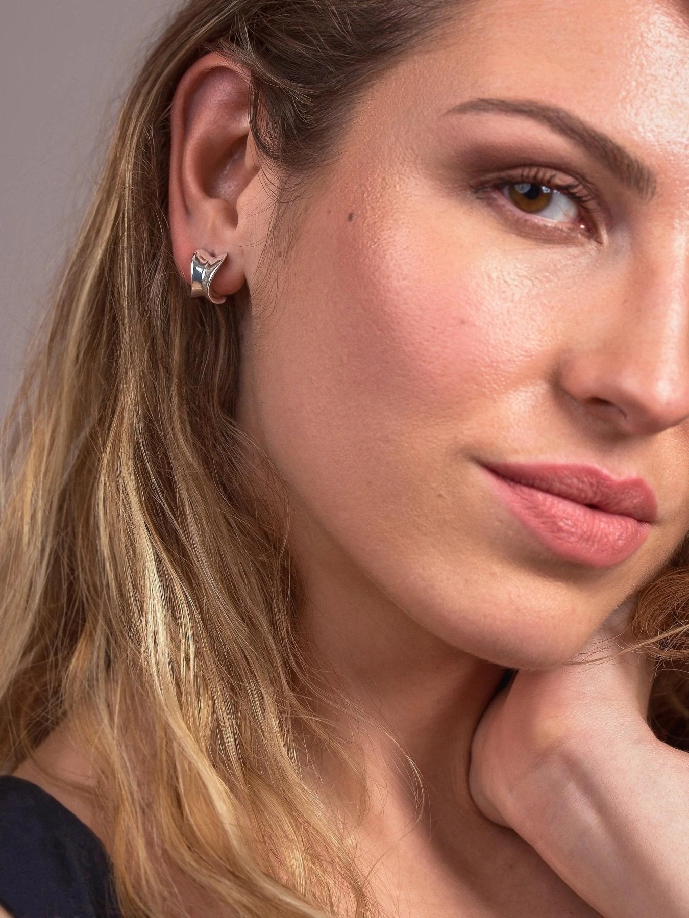 Woman wearing small silver plated chunky hoop earrings with a polished rounded finish.