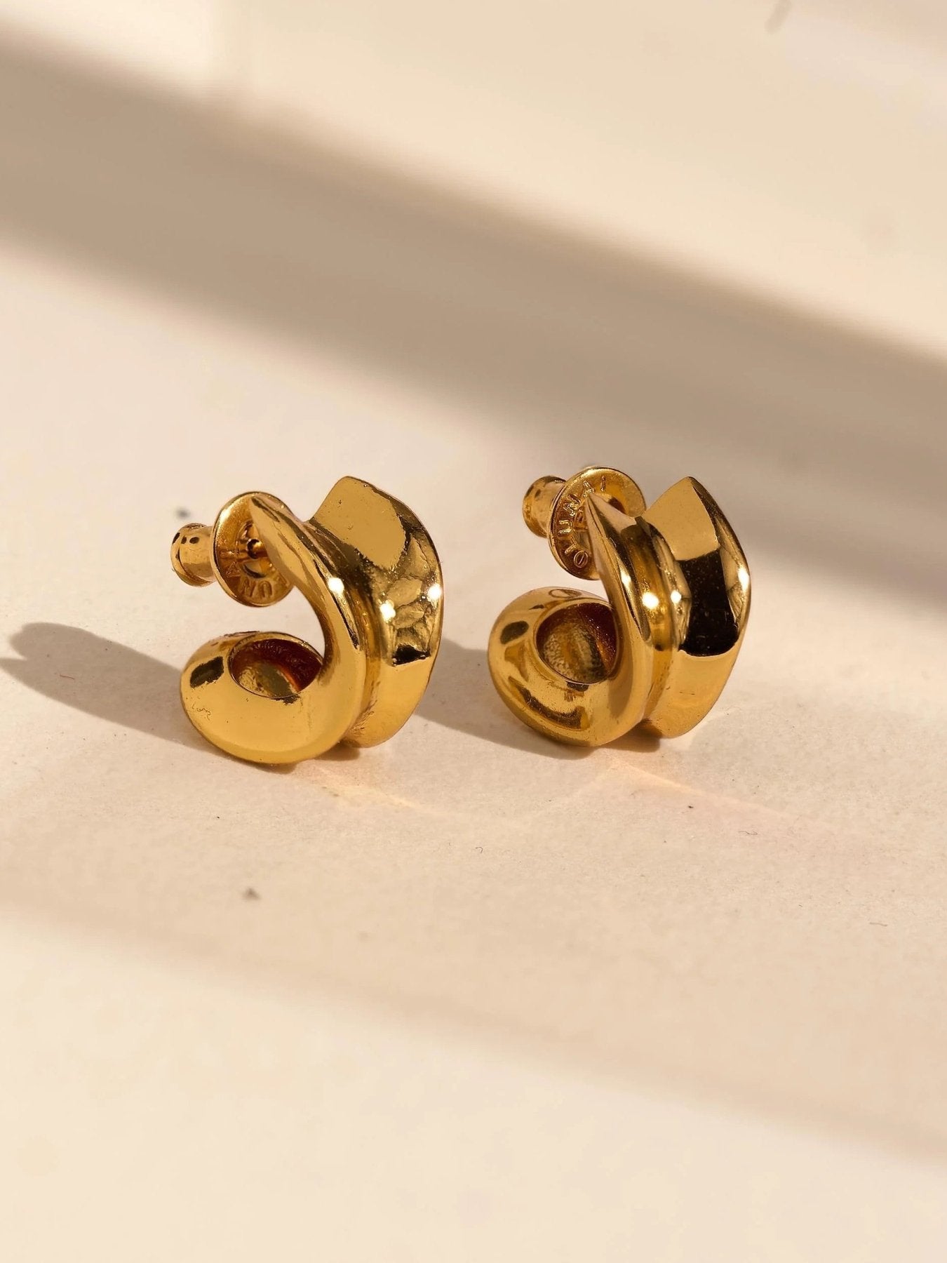 Close-up pair of petite gold hoops showing the thick rounded shape and polished finish.