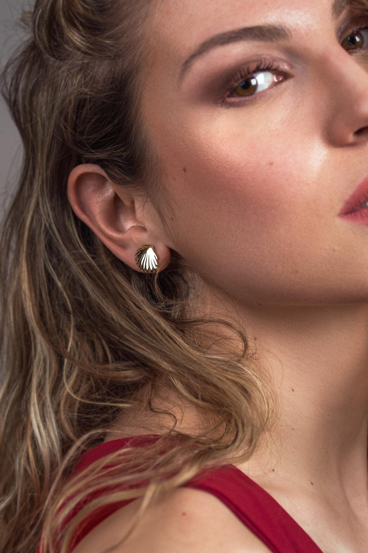 Side profile of a model wearing a silver shell stud earring, showing its petite size on the ear.