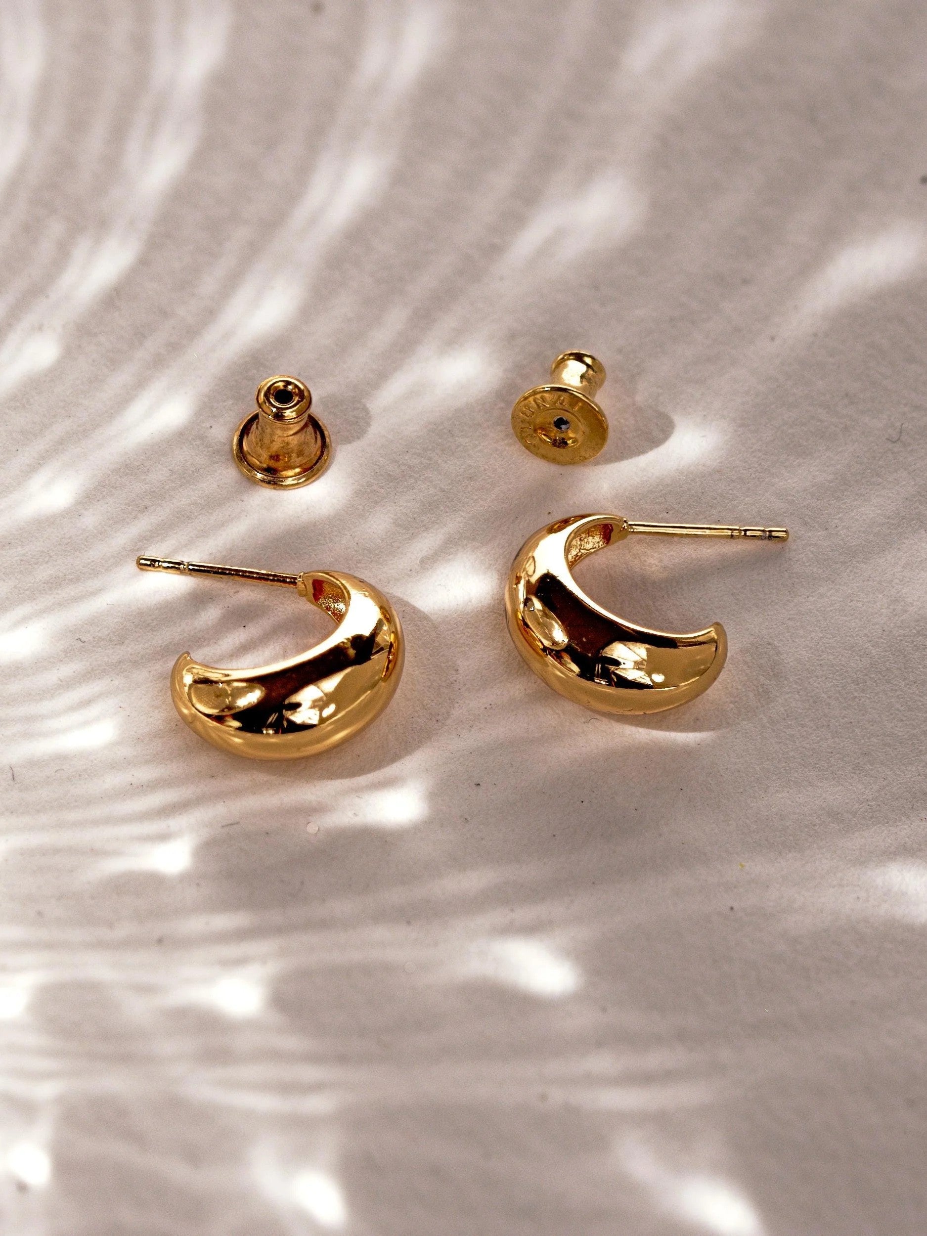 24K gold plated petite crescent hoop earrings with sterling silver posts and bell-shaped earring backs.