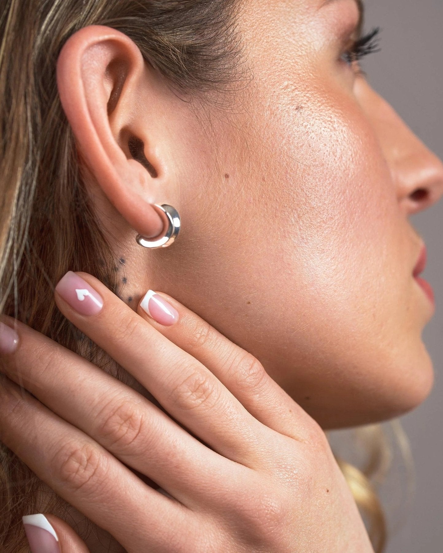 Close-up side view of petite silver chunky hoop earring showing its curved profile and size on the ear.