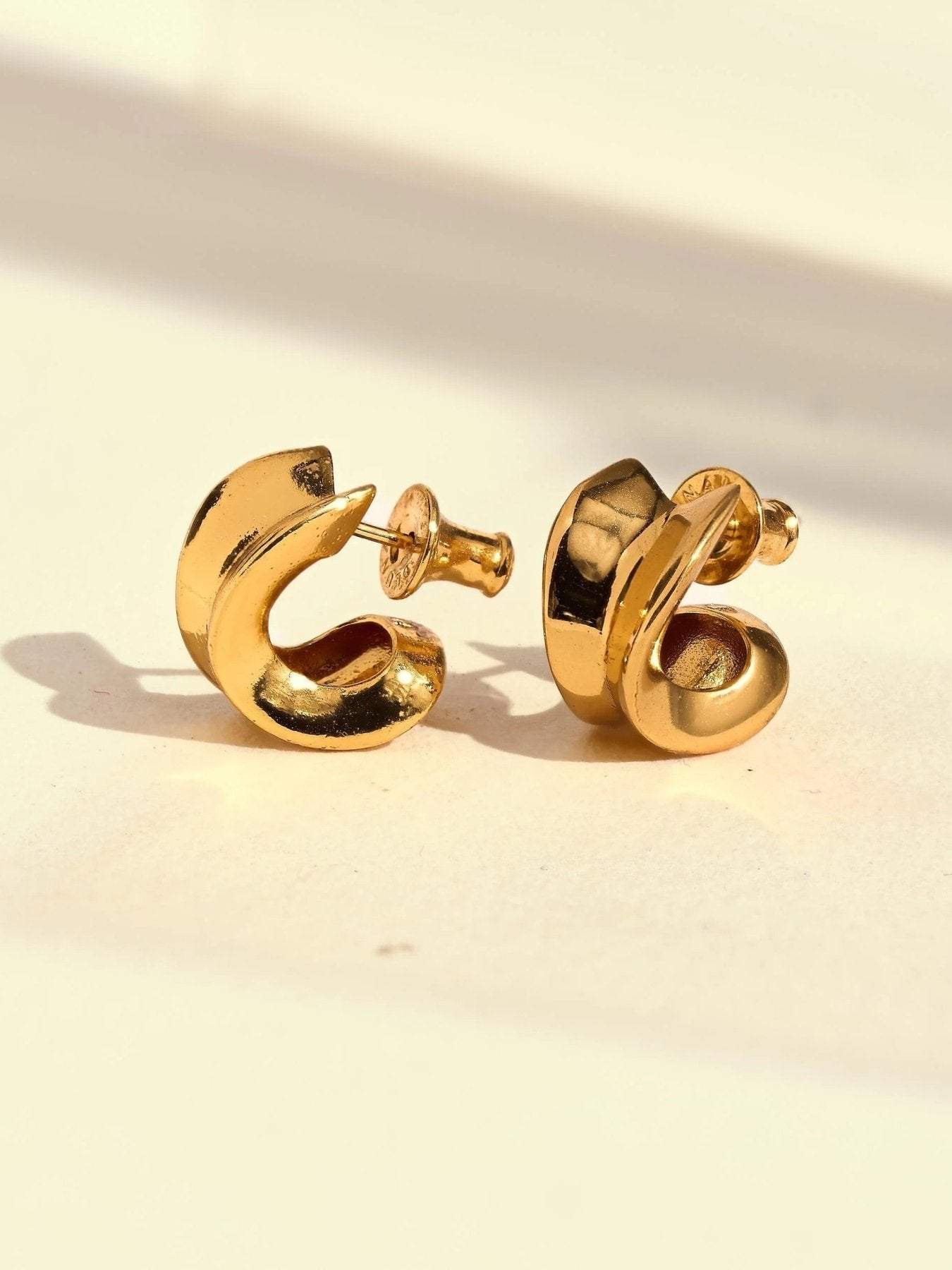 Close-up detail of gold chunky hoop earrings showing their rounded dimensional profile.