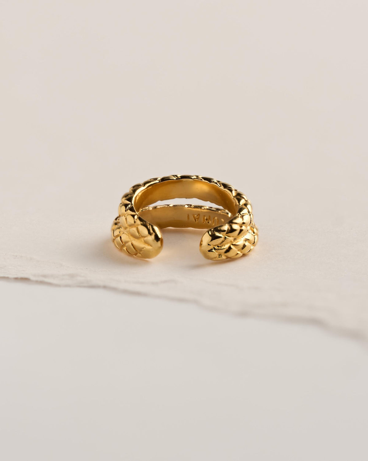Back view of a 24k gold plated brass snake ear cuff with two scale-textured snake heads at the open ends and the LUNAI stamp inside.