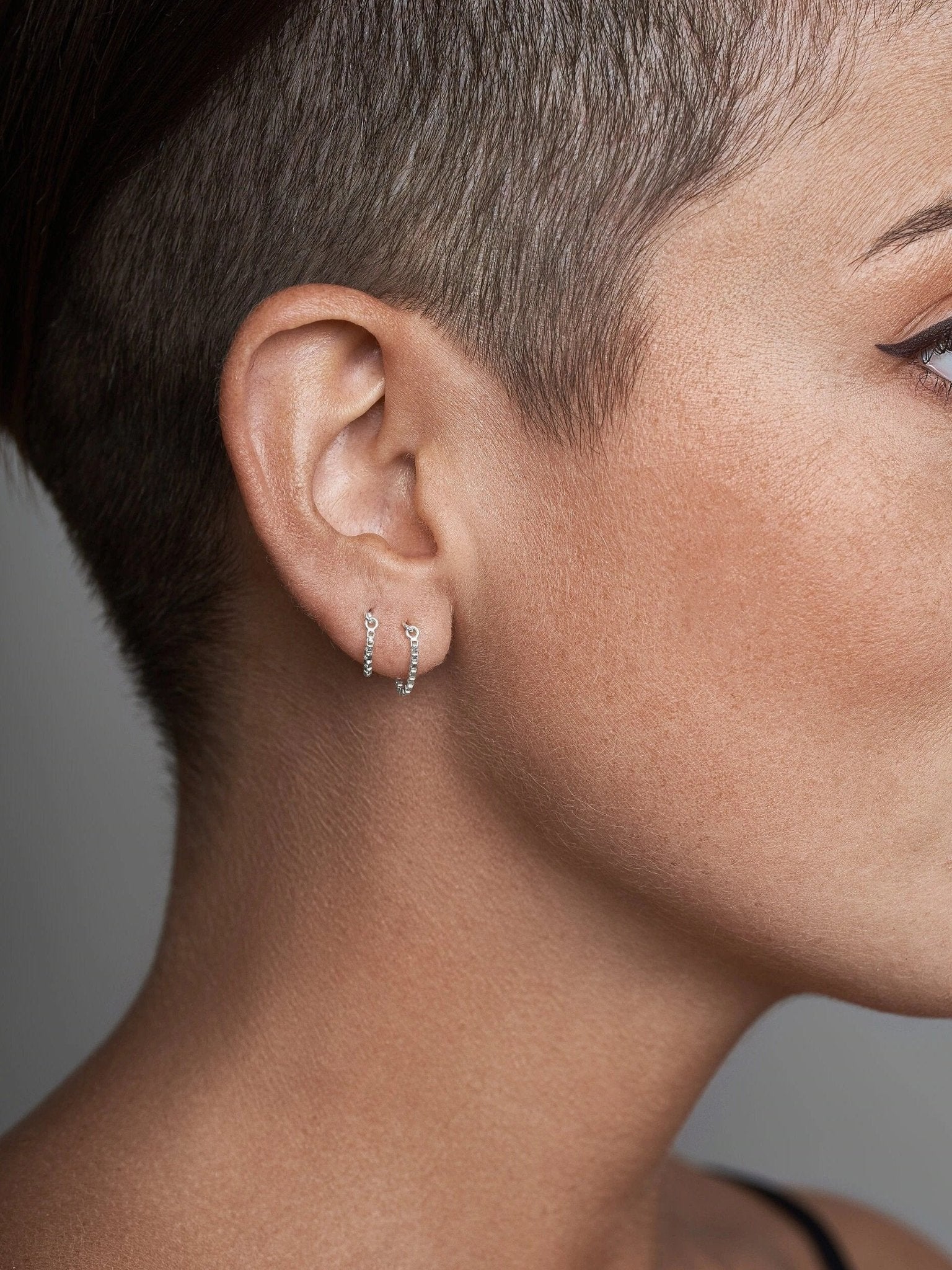 Gold chain earring on model with soft lighting and shaved cut