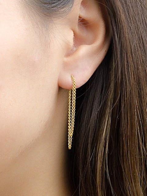 Woman wearing gold double chain earrings, side view