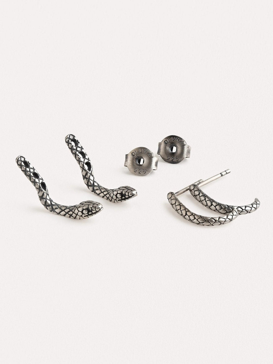 Close-up of an oxidized silver snake hoop earring on an ear, highlighting its textured details and unique shape.