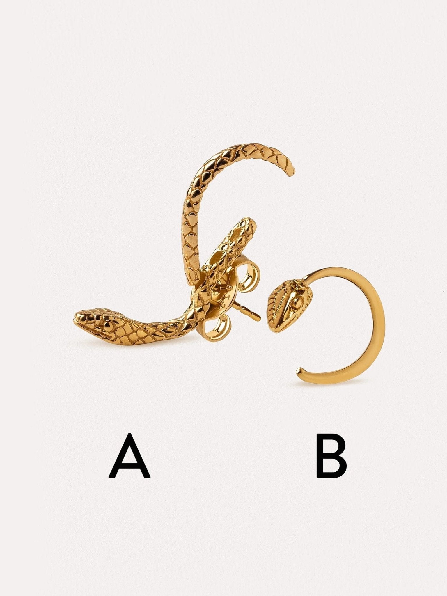 Set of two snake hoop earrings in gold, artistically arranged on a neutral surface.